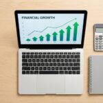 A laptop on a clean desk displaying financial growth charts next to a calculator.