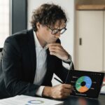 A man analyzing a colorful investment portfolio pie chart on a tablet.